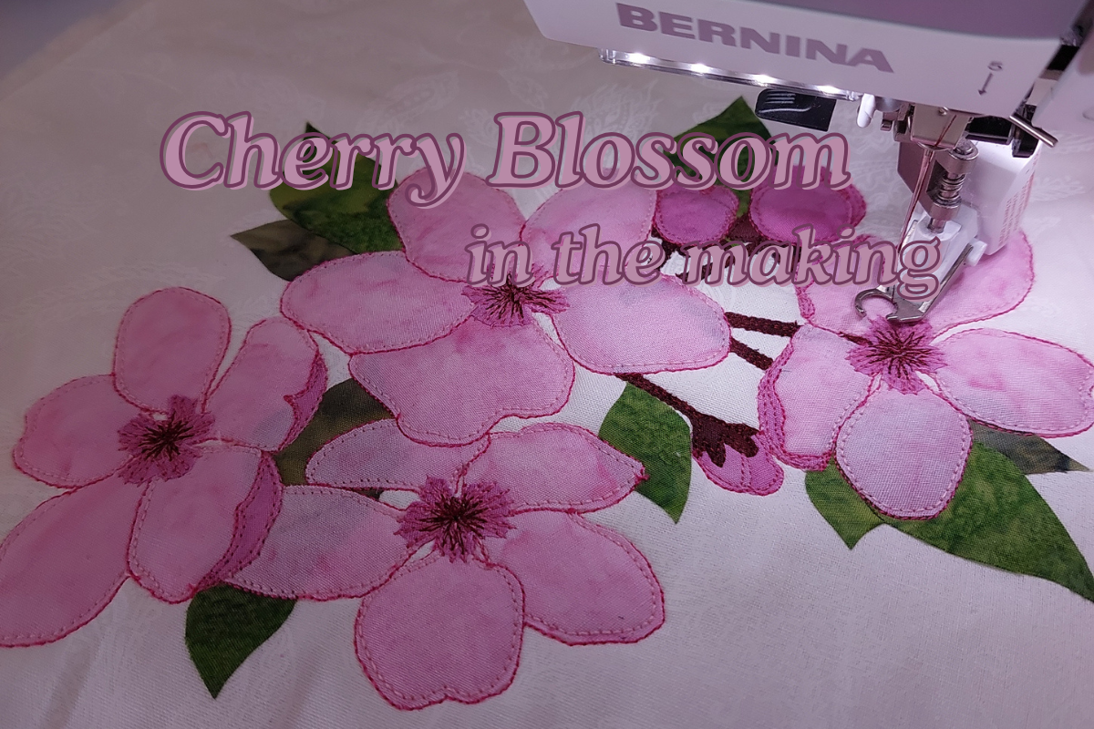 Sewing machine with pink cherry blossom flowers on a white fabric background